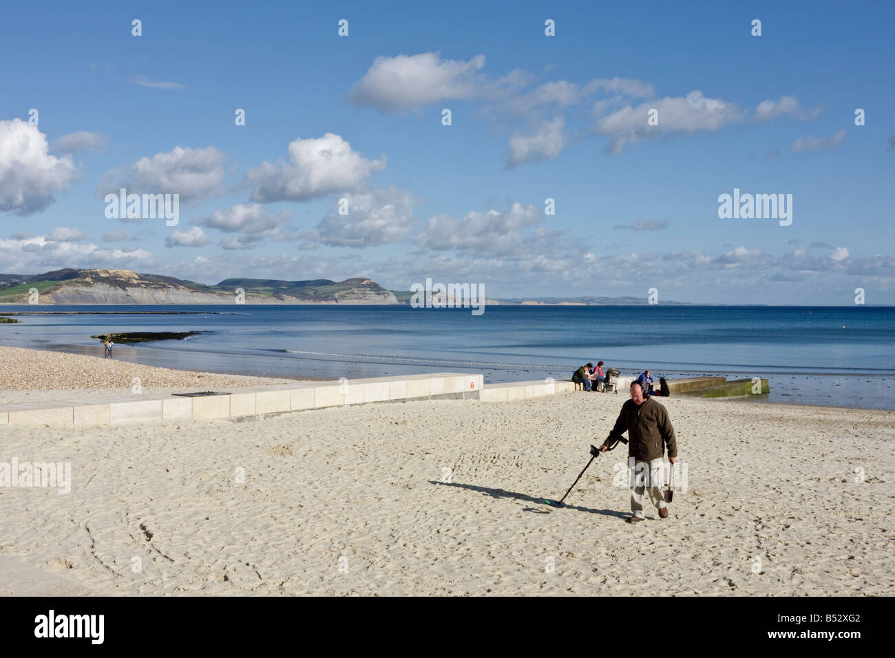 Beachcomber avec détecteur de métal recherche dans la plage de Lyme Regis Dorset sur le sable blanc avec ciel bleu. Série de 5 Banque D'Images