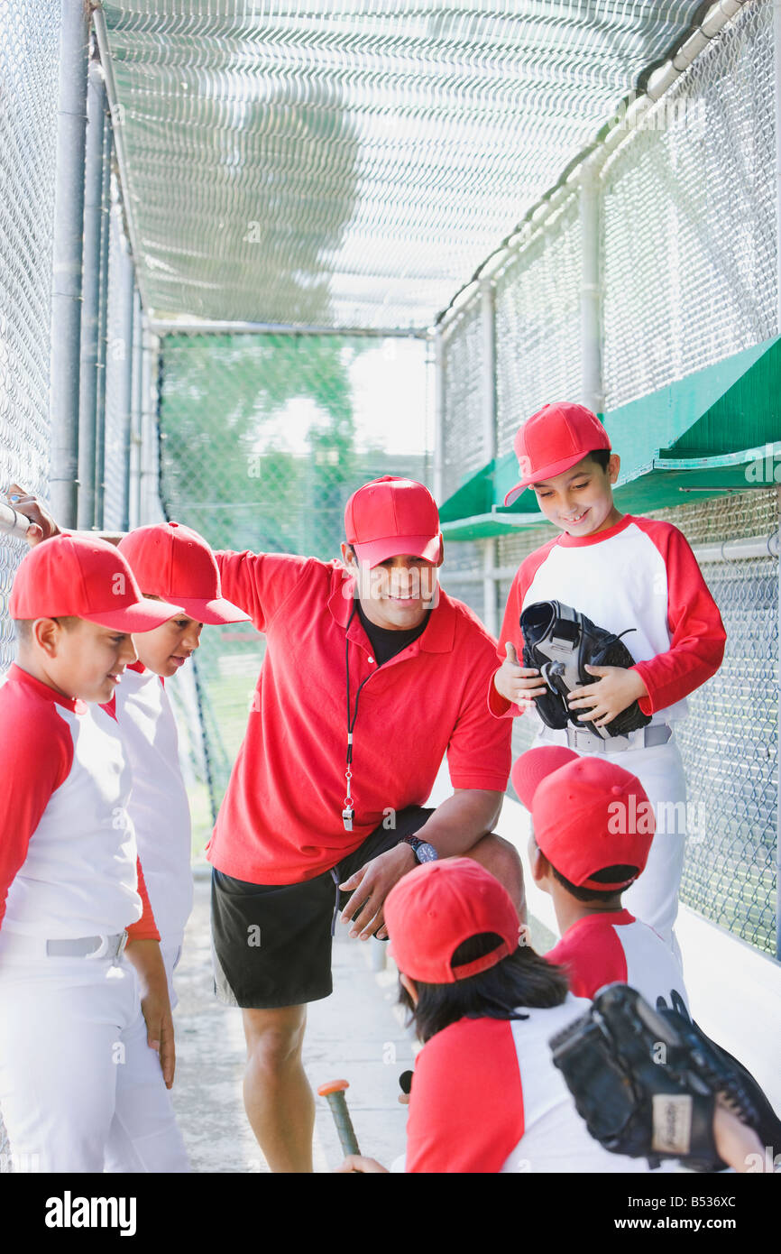 Les garçons multi-ethnique dans l'uniforme de base-ball avec l'entraîneur en pirogue Banque D'Images