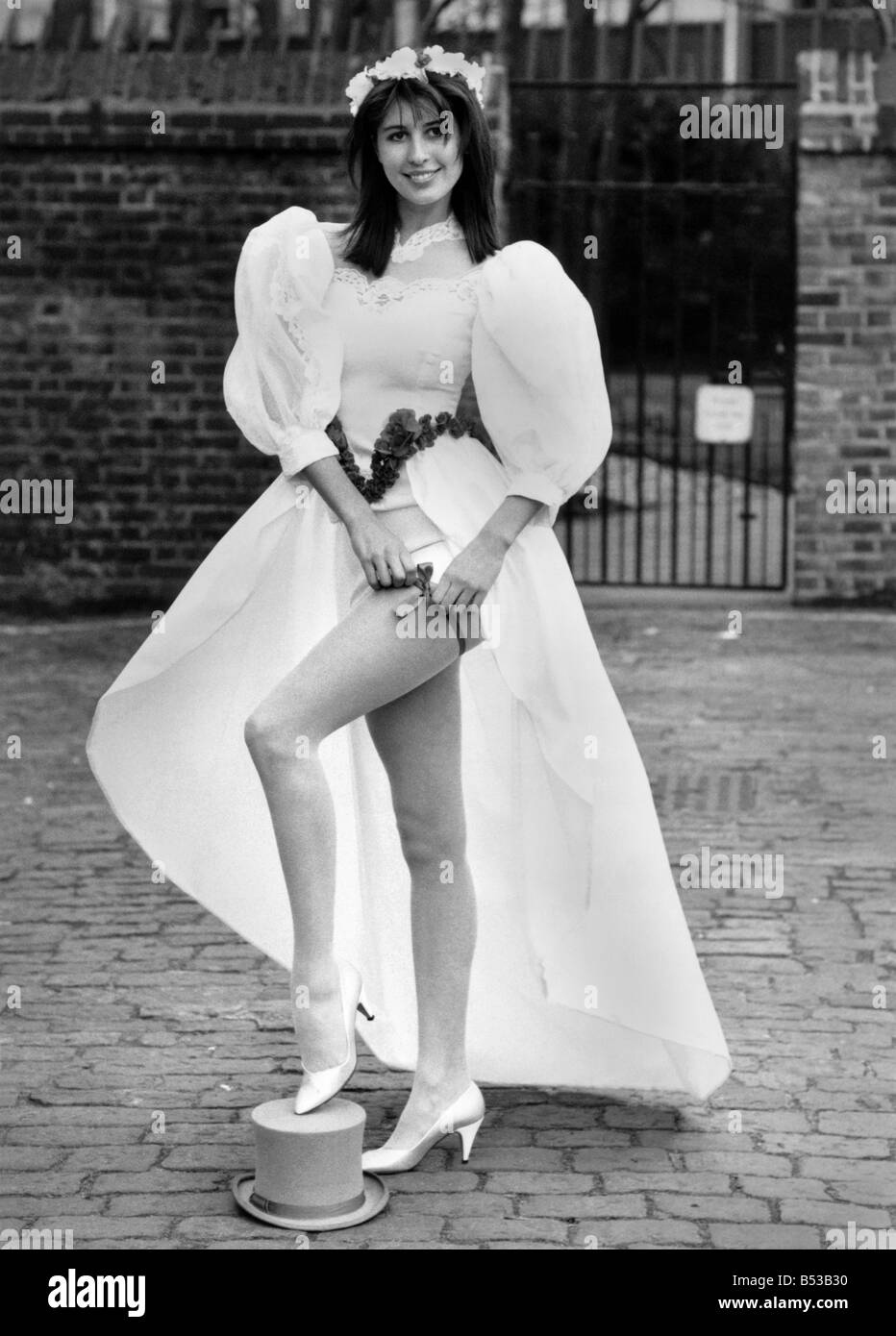 Fashion - mariage : leap de l'allée dans une mini. Modèles de mariée robe de mariage avec un long train et minidress jupe. Le pied sur le haut de forme et sa fixation jarretière.;Février 1988 P018542 Banque D'Images Fashion - mariage : leap de l'allée dans une mini. Modèles de mariée robe de mariage avec un long train et minidress jupe. Le pied sur le haut de forme et sa fixation jarretière.;Février 1988 P018542 Banque D'Images