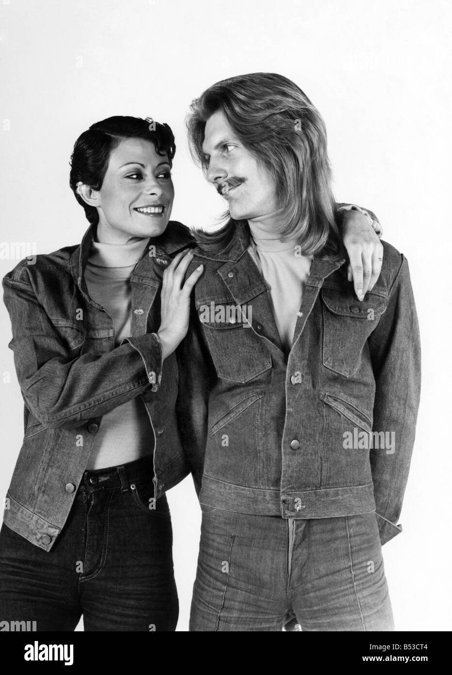- La mode des années 70 : l'homme qu'elle. Elle est prise en charge de lui ? ;Couple wearing jeans et vestes en denim.;l'homme aux cheveux longs et moustache. Femme aux cheveux courts.;Mars 1976 P017328 Banque D'Images