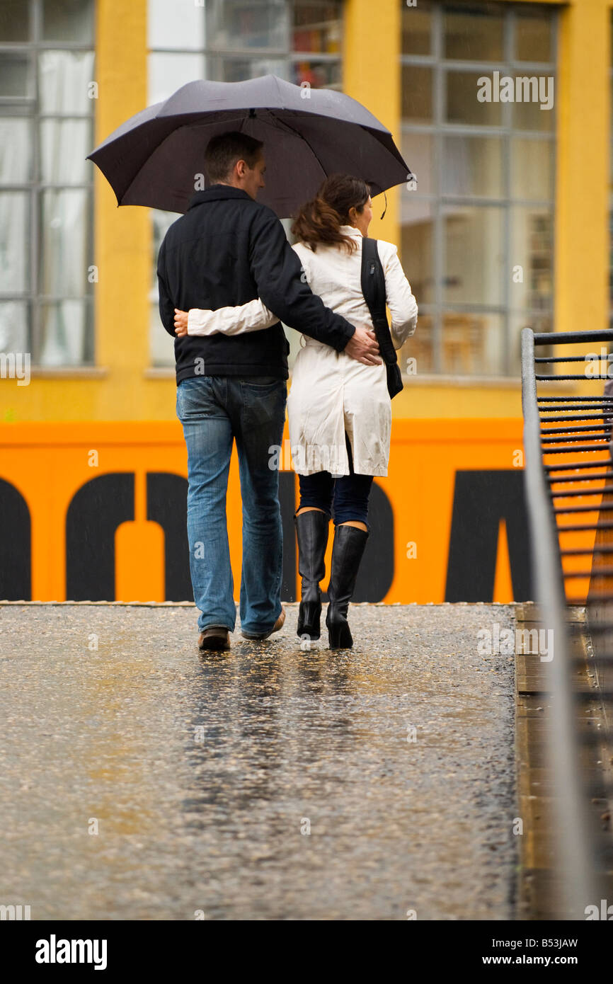 Un jour de pluie à Londres , young couple marche bras dessus bras dessous sous grand parapluie noir Banque D'Images