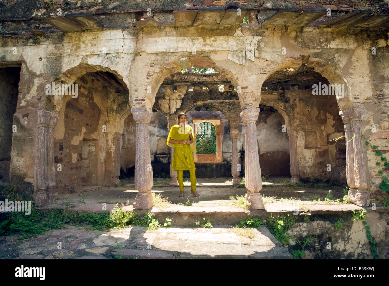 Une jeune indienne traditionnelle en costume jaune se tient entre les arches dans le Fort, le parc national de Ranthambore, en Inde Banque D'Images