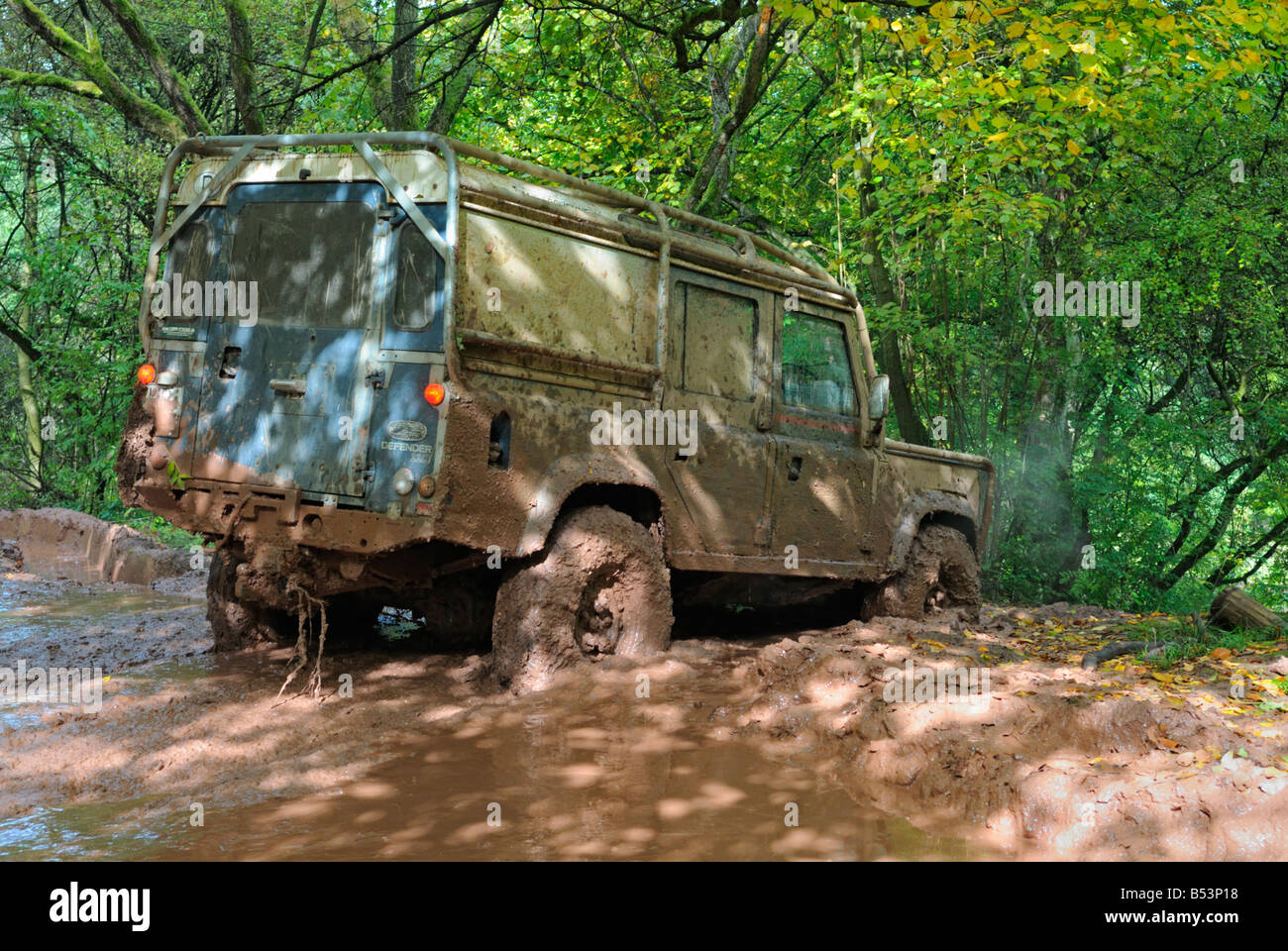 Land Rover Defender 110 boueux en passant par la boue profonde sur une piste forestière dans le Weserbergland. Banque D'Images