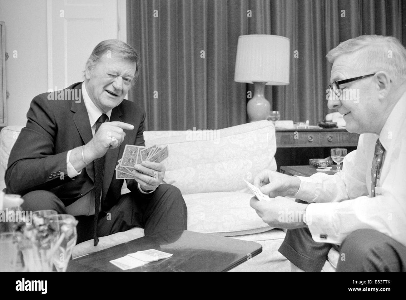 La photo de John Wayne relaxing cartes à jouer dans sa suite à l'hôtel Connaught, Mayfair, Londres. Janvier 1974. Banque D'Images