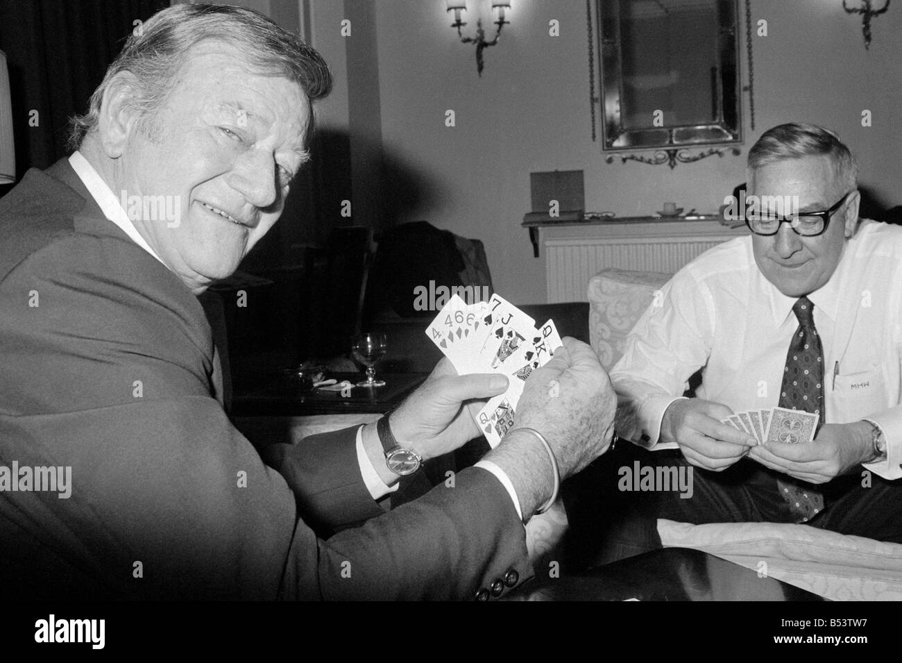 La photo de John Wayne relaxing cartes à jouer dans sa suite à l'hôtel Connaught, Mayfair, Londres. Janvier 1974. Banque D'Images