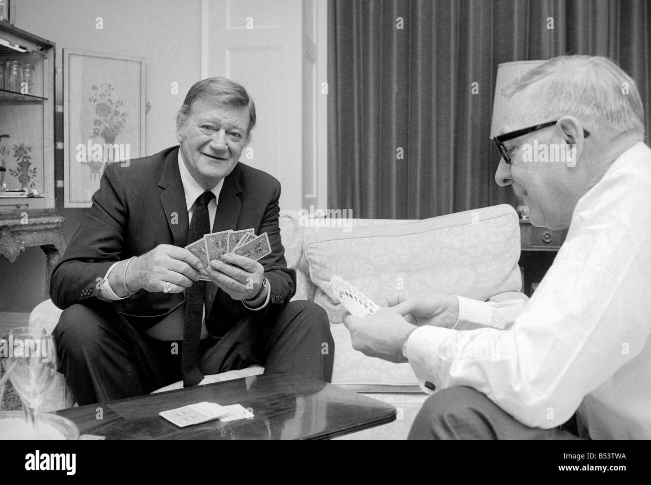 La photo de John Wayne relaxing cartes à jouer dans sa suite à l'hôtel Connaught, Mayfair, Londres. Banque D'Images