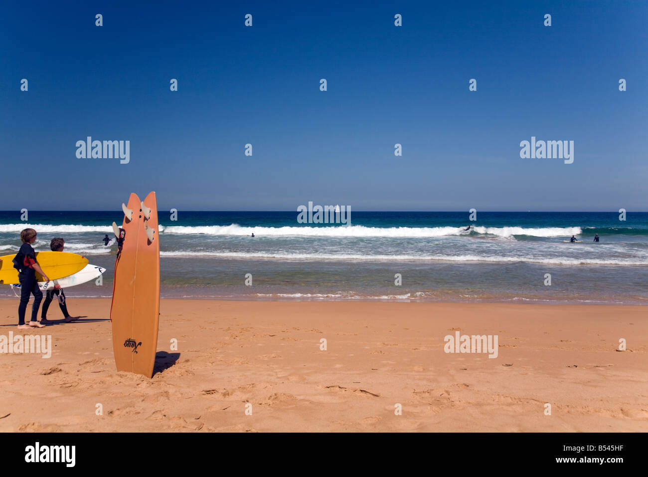 Ciel bleu profond sur bungan beach, Sydney, Australie, deux jeunes garçons à pied avec leurs planches de surf Banque D'Images
