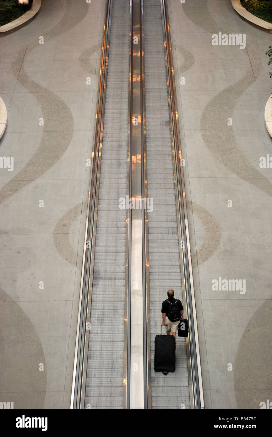Homme avec valise roulant sur une passerelle dans un aéroport Banque D'Images