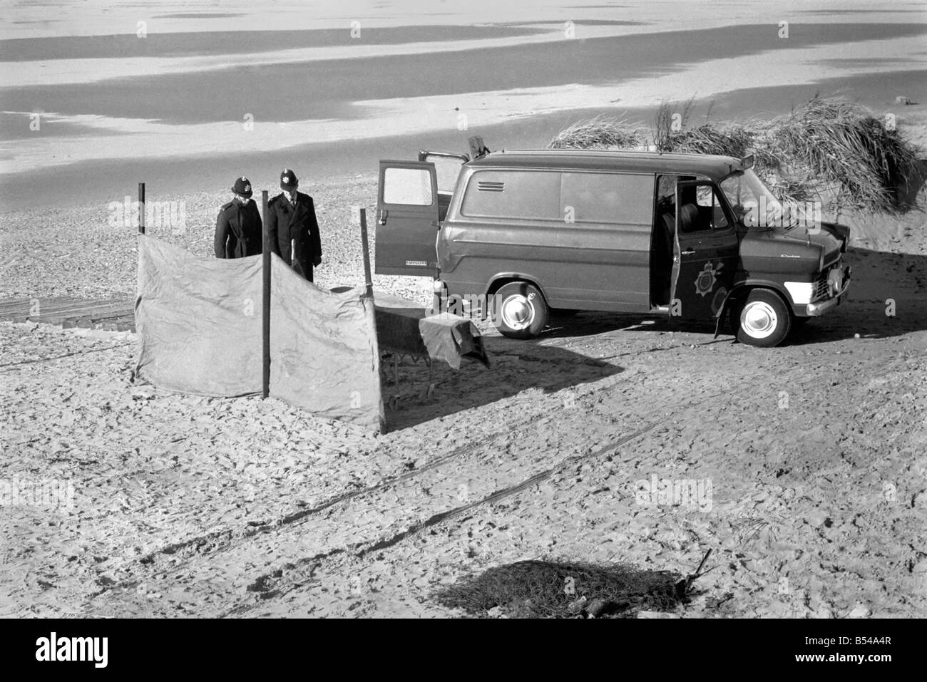 Femme morte trouvée sur la plage au fleuve Annexe. Scène de la tragédie montrant brûlé reste de ce qui semble être un matelas, un cercueil derrière des écrans, et un fourgon de police sur les lieux, gardé par des policiers. ;Novembre 1969 ;Z10766-001 Banque D'Images