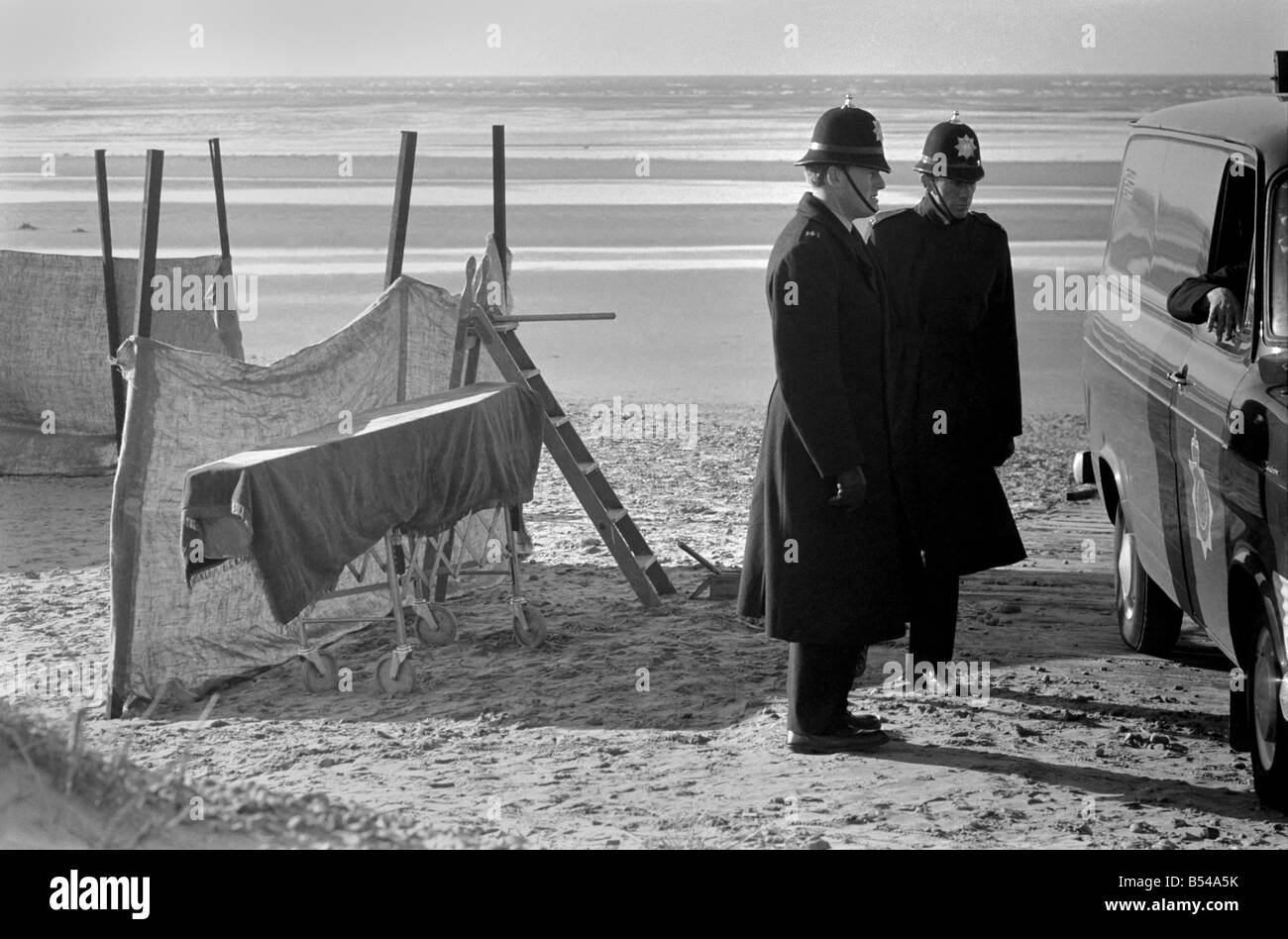 Femme morte trouvée sur la plage au fleuve Annexe. Scène de la tragédie montrant brûlé reste de ce qui semble être un matelas, un cercueil derrière des écrans, et un fourgon de police sur les lieux, gardé par des policiers. ;Novembre 1969 ;Z10766 Banque D'Images