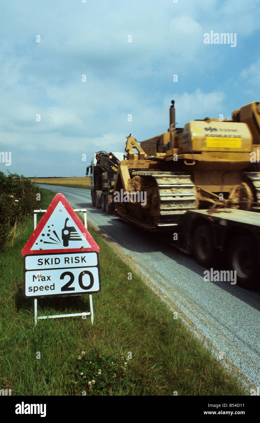 Camion transport terrassement géant passé panneau d'avertissement de risque de dérapage sur route de campagne nouvellement refait surface près de Leeds Yorks Banque D'Images