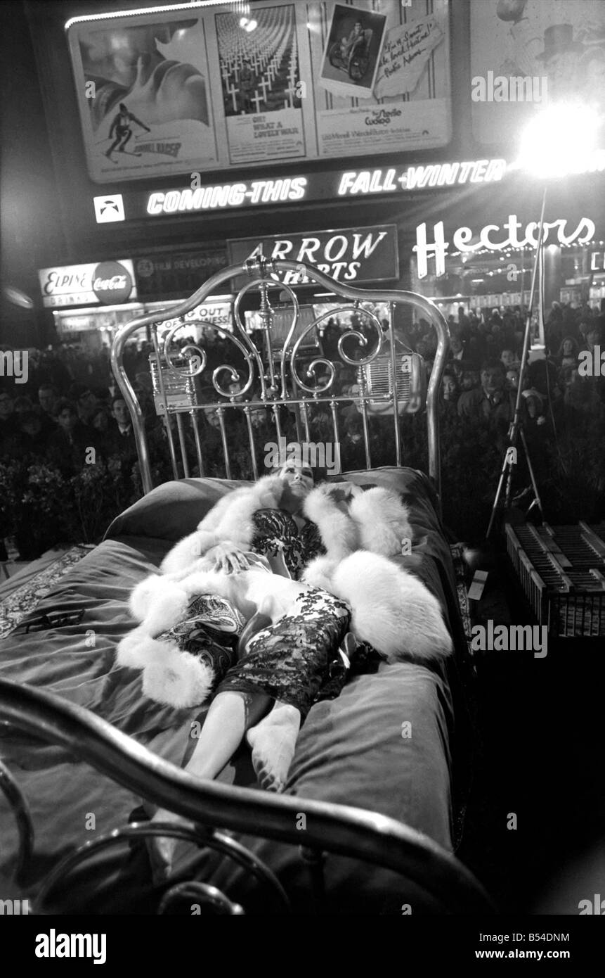 L'actrice Julie Newmar allongé sur un lit en cuivre dans le New York Times Square pour une scène dans le film 'McCloud'. Novembre 1969 Z11482-002 Banque D'Images