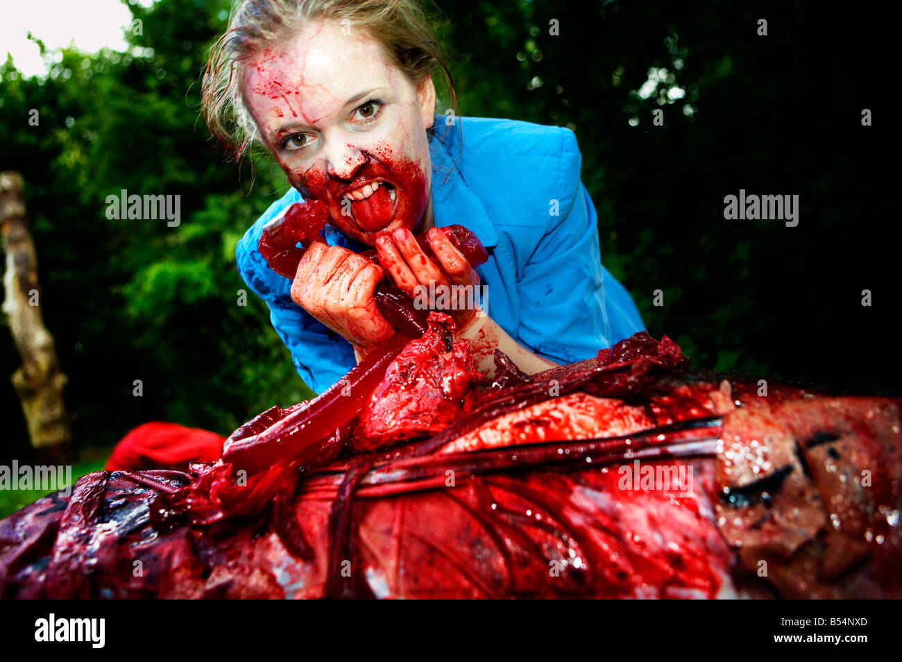 Une femme vêtue comme un zombie mange un homme mort Banque D'Images