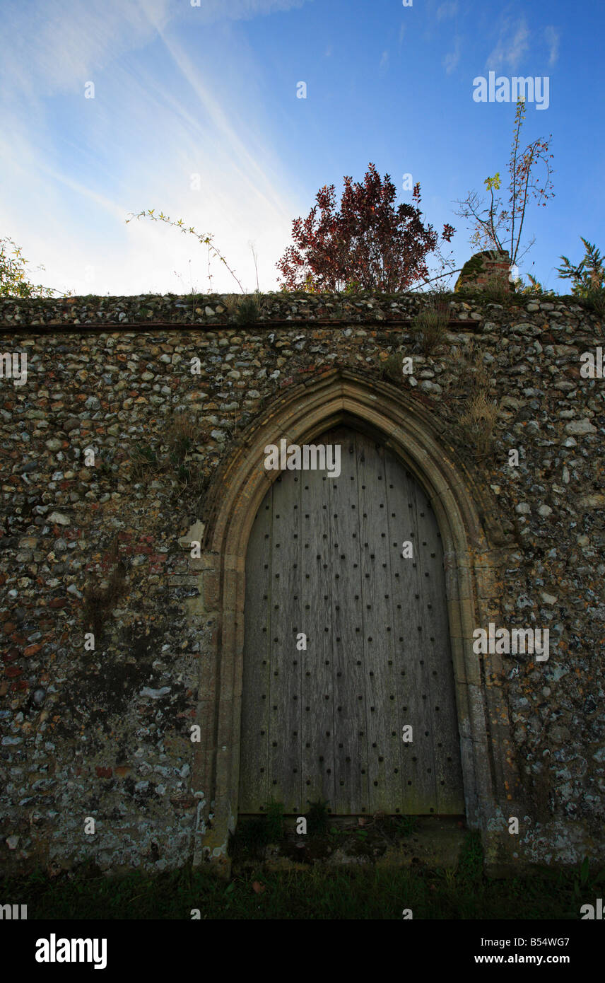 Une porte en bois dans un vieux mur à silex Creake Abbaye, Norfolk, Angleterre. Banque D'Images