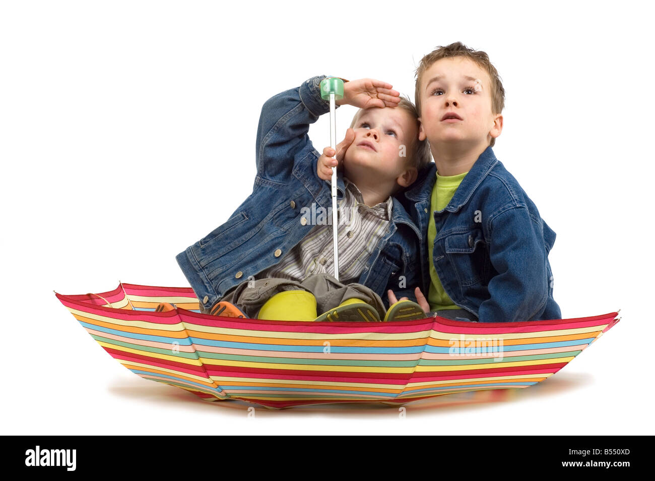 Deux garçons assis dans un parapluie comme il s'agit d'un bateau qu'ils re regarder si la tempête s'en vient Banque D'Images