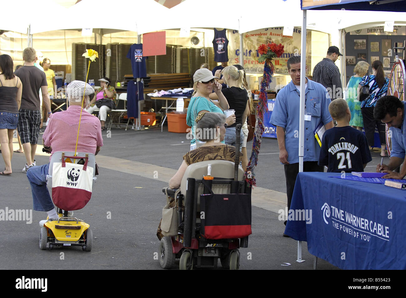 Un couple de personnes âgées bénéficie d'un voyage à un événement public à leur mobilité scooter et fauteuil roulant motorisé. Banque D'Images