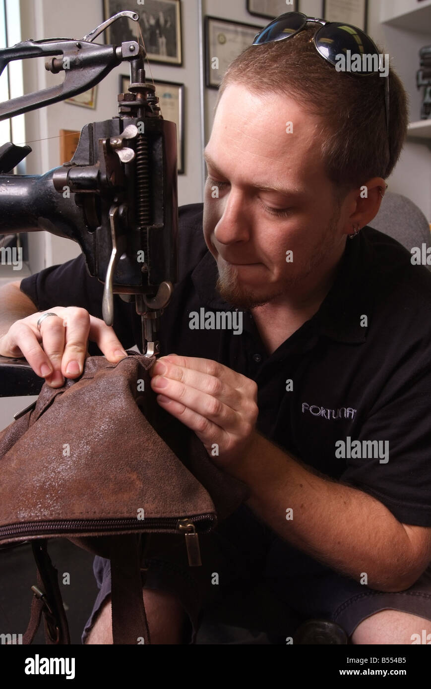 Un homme utilise une ancienne machine à coudre Singer pour réparer les objets en cuir dans un petit magasin dans le Maryland USA Banque D'Images