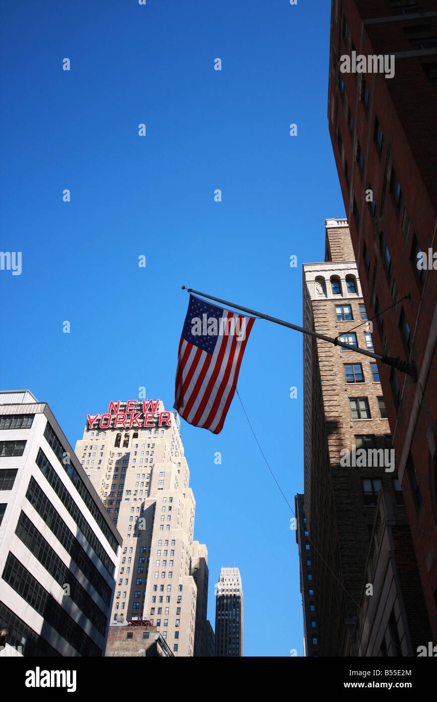 US flag against blue sky New Yorker Hotel en arrière-plan Banque D'Images