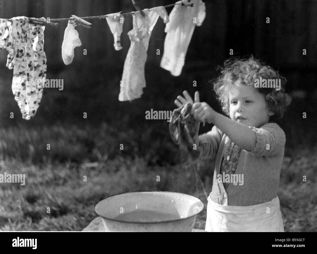 Jeune fille à laver ses vêtements dans un bol d'eau et les accrocher à sécher sur l'étendoir;Circa 1945;P044431 Banque D'Images