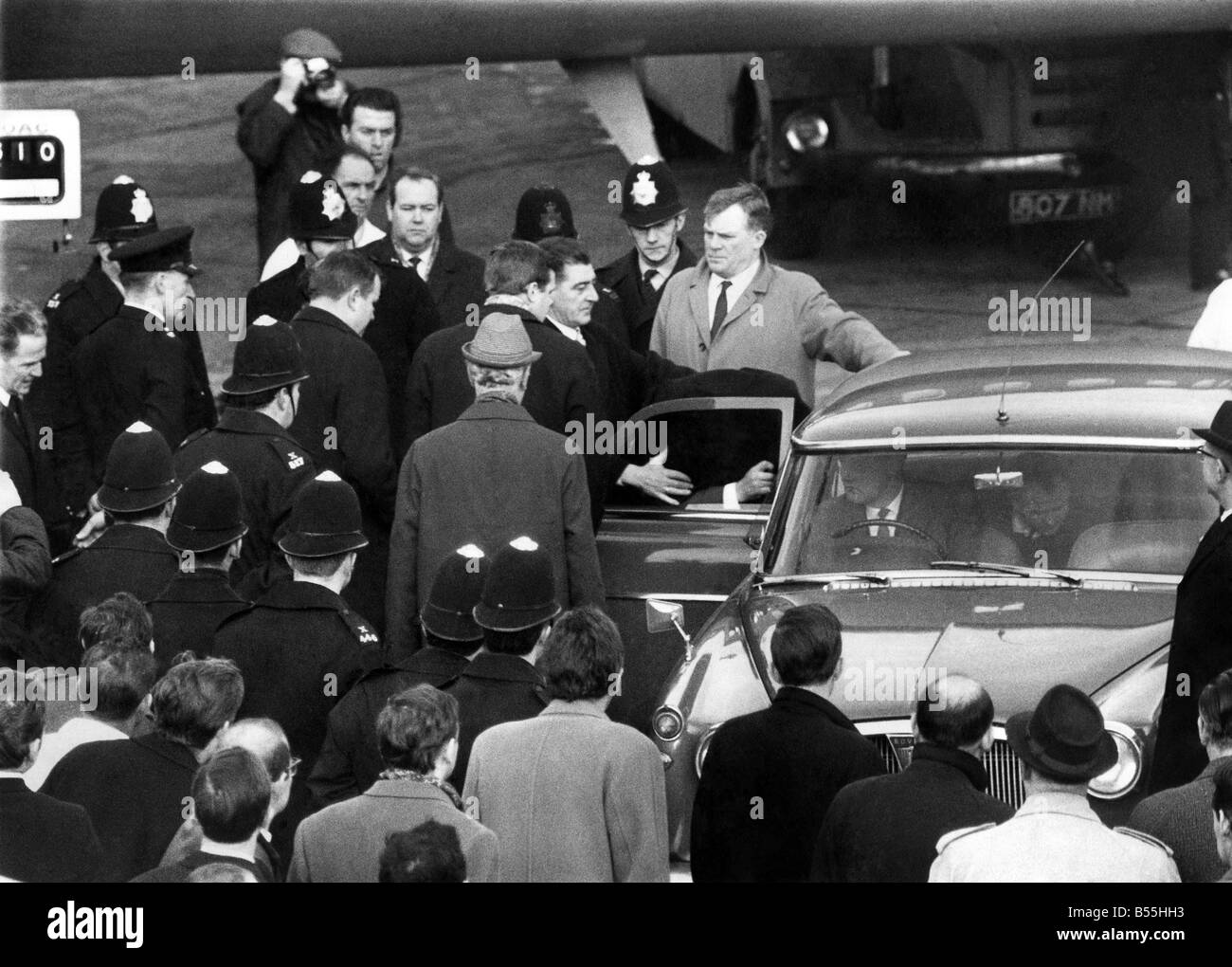 Great Train Robber Charles Wilson avec un manteau sur la tête d'entrer dans une voiture de police sur le tarmac de l'aéroport d'Heathrow Londres après son arrivée en provenance du Canada. Janvier