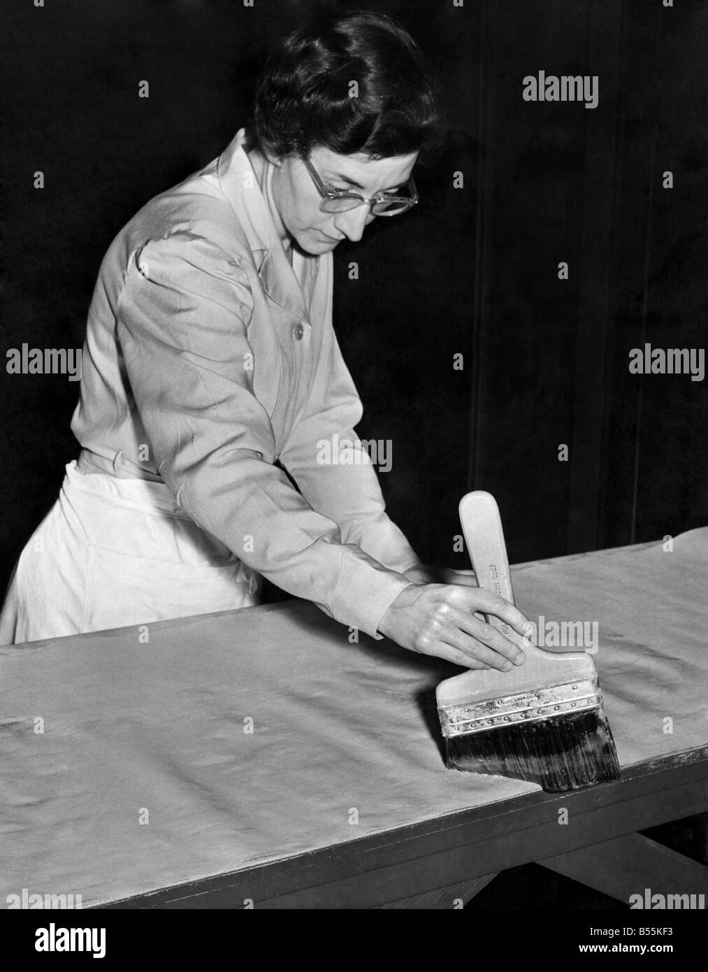 Collage, voir que le papier est en ligne avec le bord de la table. Le brossage d'un centre à l'extérieur, ce qui en fait une distribution homogène de la pâte. Novembre 1953 P009526 Banque D'Images