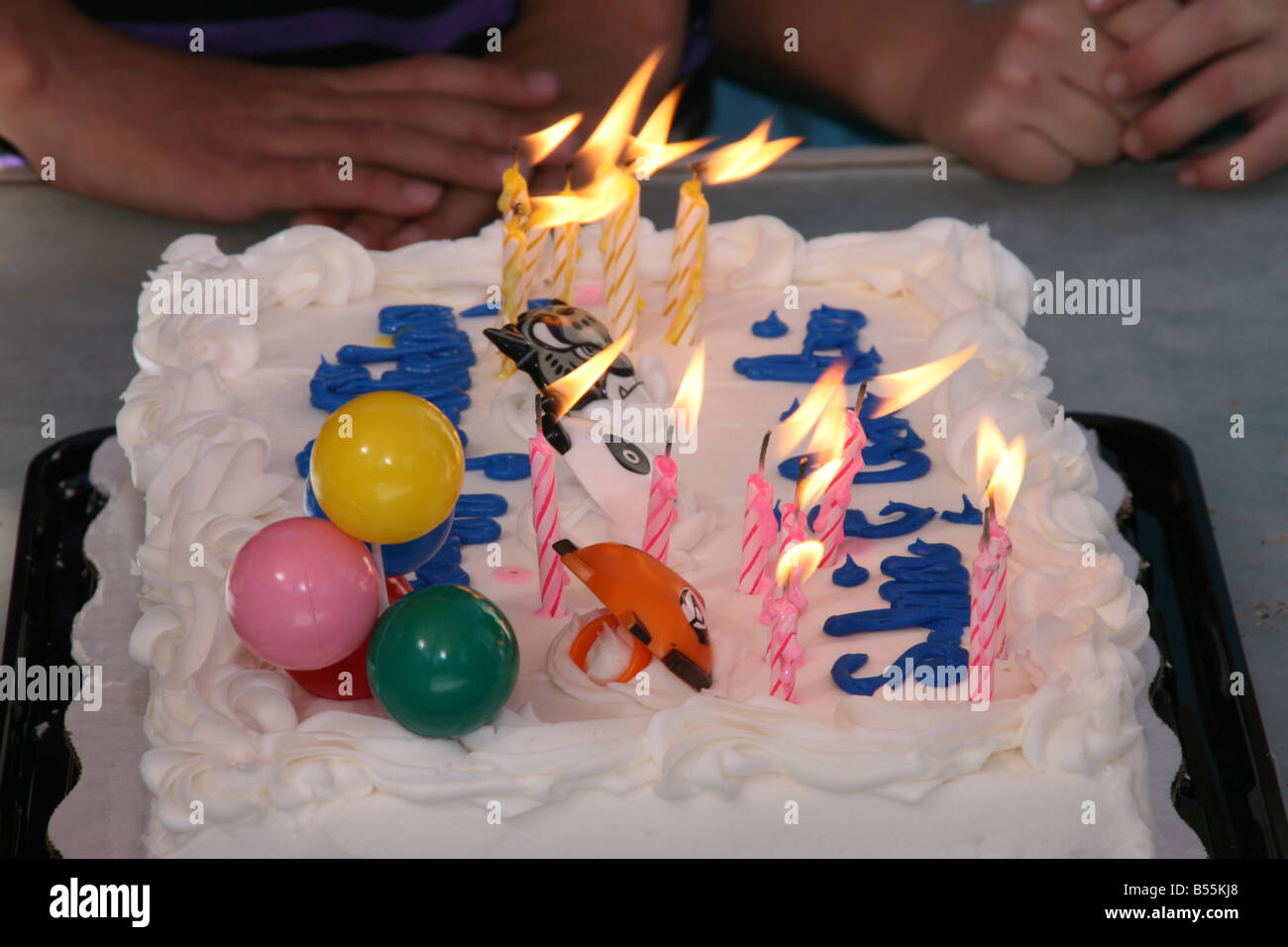 Gâteau d'anniversaire avec des bougies, des mains des enfants attendent patiemment Banque D'Images