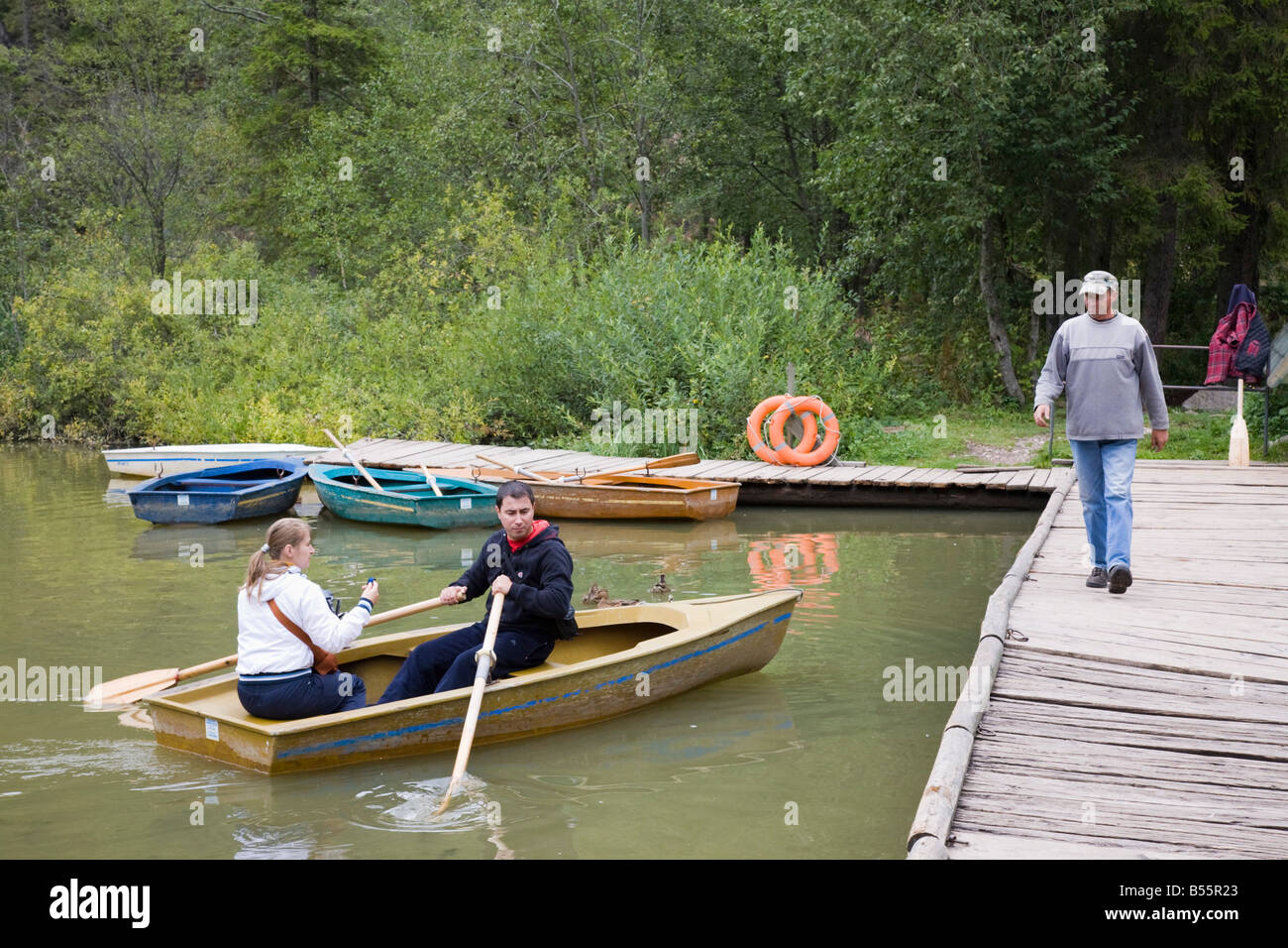 La Moldavie Roumanie Les gens en bateau à rames location chalet en bois par jetée sur 'Red Lake' dans les gorges du Bicaz Hasmas 'National Park' Banque D'Images