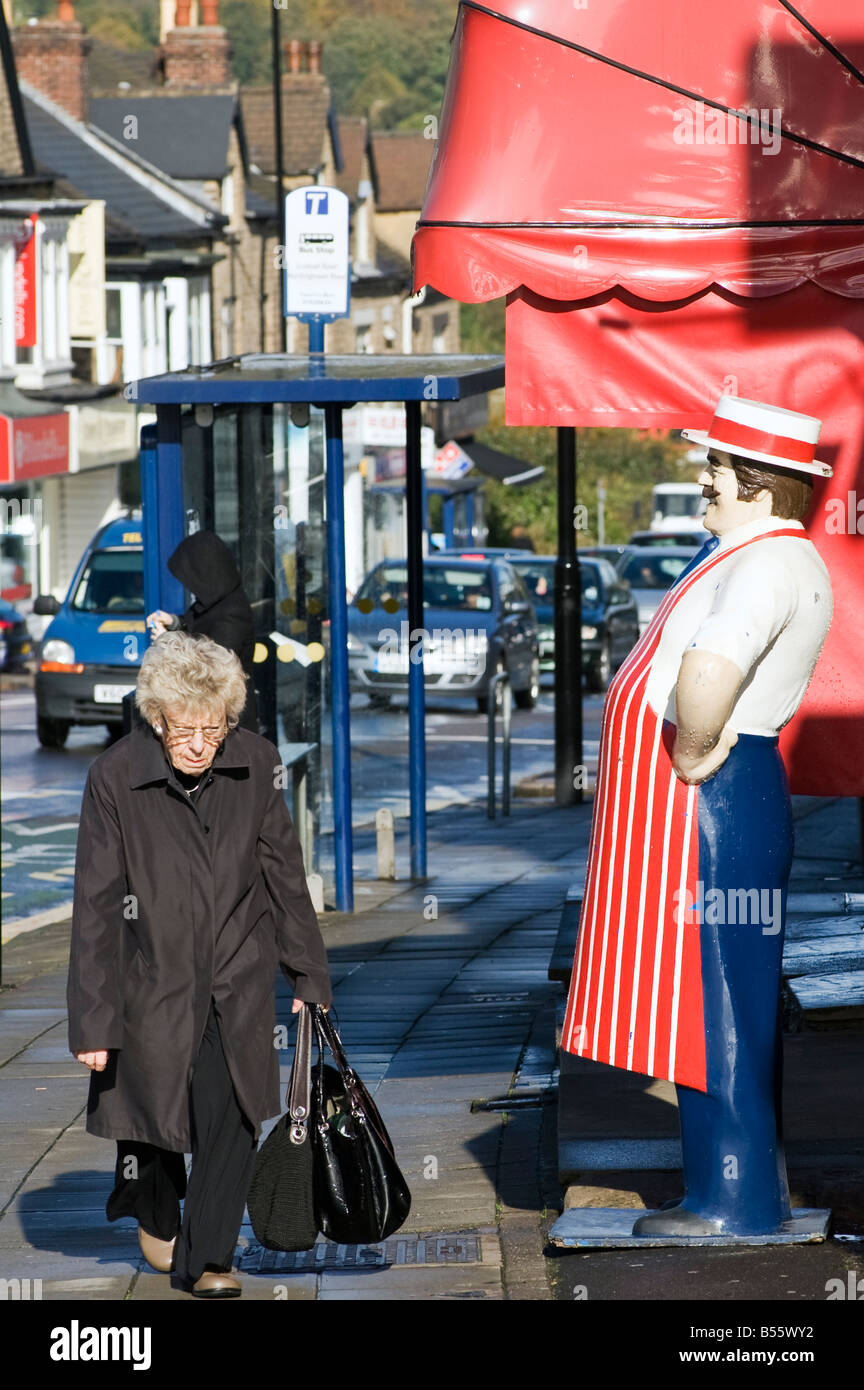 Femme portant des courses à l'extérieur d'une boucherie avec un boucher modèle Banque D'Images