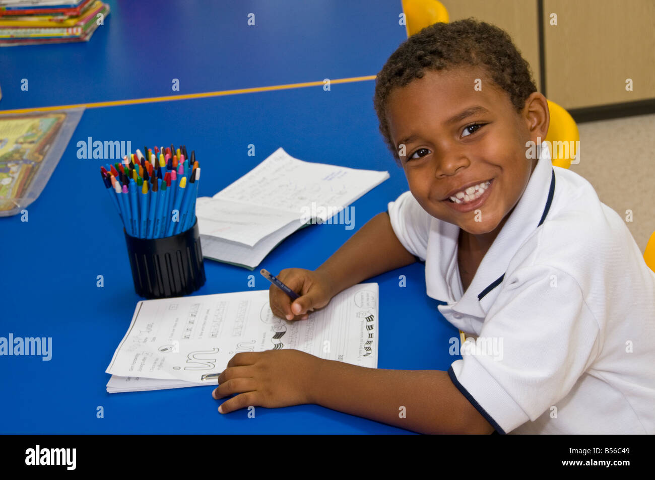 Jeune Afro-américain école noire apprendre à écrire à un bureau dans la classe de maternelle école Banque D'Images