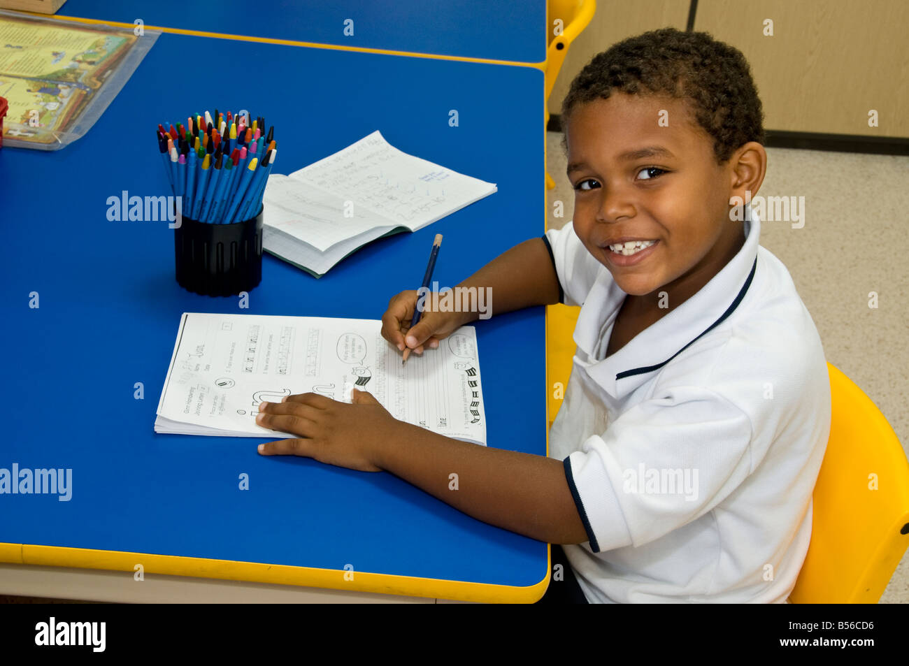 Garçon d'école bébé afro-américain 4-6 ans confiant garçon noir heureux portant l'uniforme, apprenant à écrire au bureau dans la salle de classe de réception de maternelle Banque D'Images