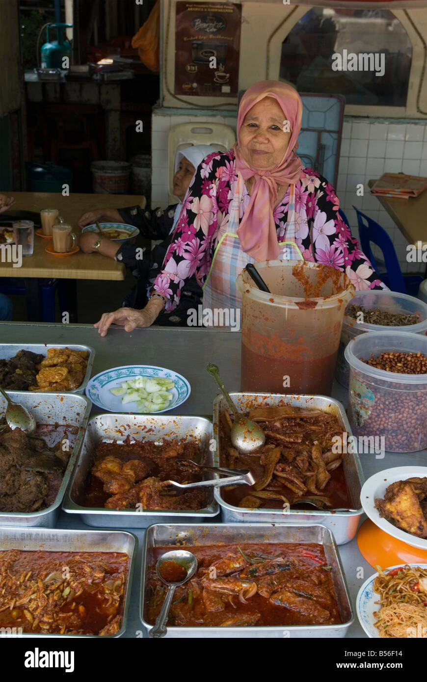 Un food propriétaire affiche ses plateaux de nourriture dans un food hall dans la zone traditionnelle malaisienne de Kampung Baru, Kuala Lumpur, Malaisie Banque D'Images