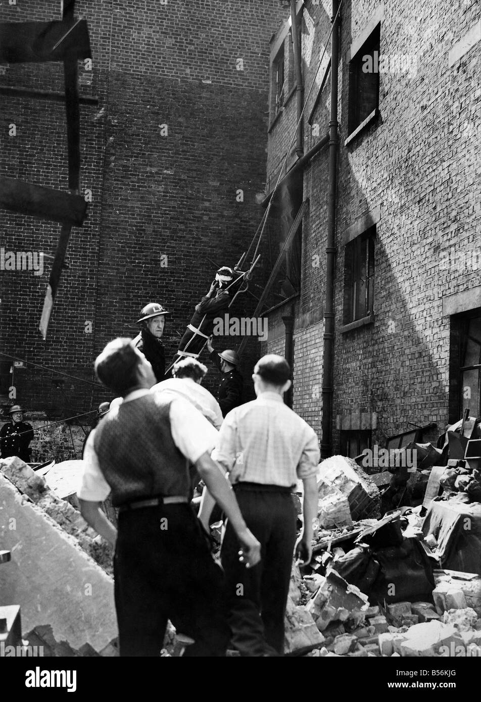 Lorsqu'un bâtiment a été touché dans un raid sur ce pays pompiers abaissé un homme blessé à partir de la toiture après qu'ils ont secouru des débris qu'il a été transporté à l'hôpital, Janvier 1944 P009376 Banque D'Images