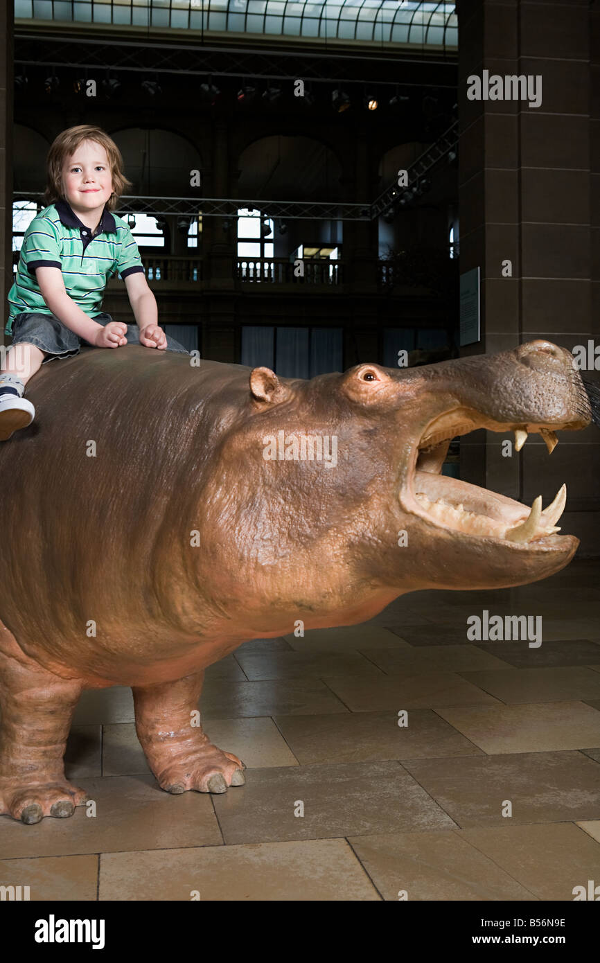 Garçon assis sur un rhinocéros dans un musée Banque D'Images