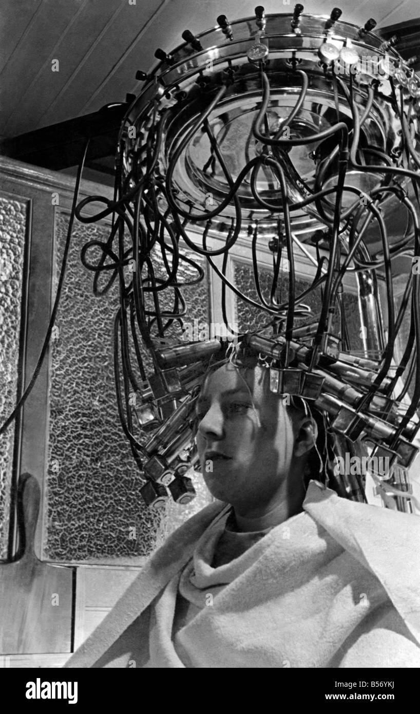 Coiffure automatique machine;nous voyons ici la machine en position avec jackets couplé à des tubes à vapeur. Le chef de la machine se compose d'une série de chaudières qui sont chauffés à l'électricité. Après ébullition passe de la vapeur chaudières le caoutchouc tubes dans les vestes. À aucun moment durant le processus est le client en contact avec un courant électrique. Avril 1936 P010028 Banque D'Images