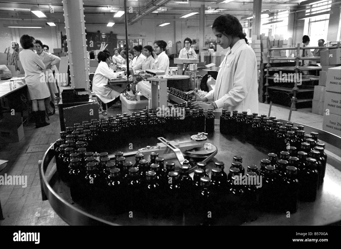 La recherche médicale : Une médecine célèbre les fabricants travaillent à plein régime pour faire face à la grippe aviaire epedemic. Leur remède contre la toux bien connu qui est prescrite par la plupart des médecins était de plus en plus difficile à obtenir, pour une formation complète les pharmaciens se sont portés volontaires pour aider à la mise en bouteille de ce médicament. Ces pharmaciens travaillent dans l'entreprise, Parke-Davis & Co., d'Hounslow, Middlesex et sont maintenant en train de mettre des étiquettes et bouchons sur le médicament... un travail normalement effectué par les femmes. 30 de leurs femmes sont là avec la grippe. Décembre 1969 Z12497-003 Banque D'Images