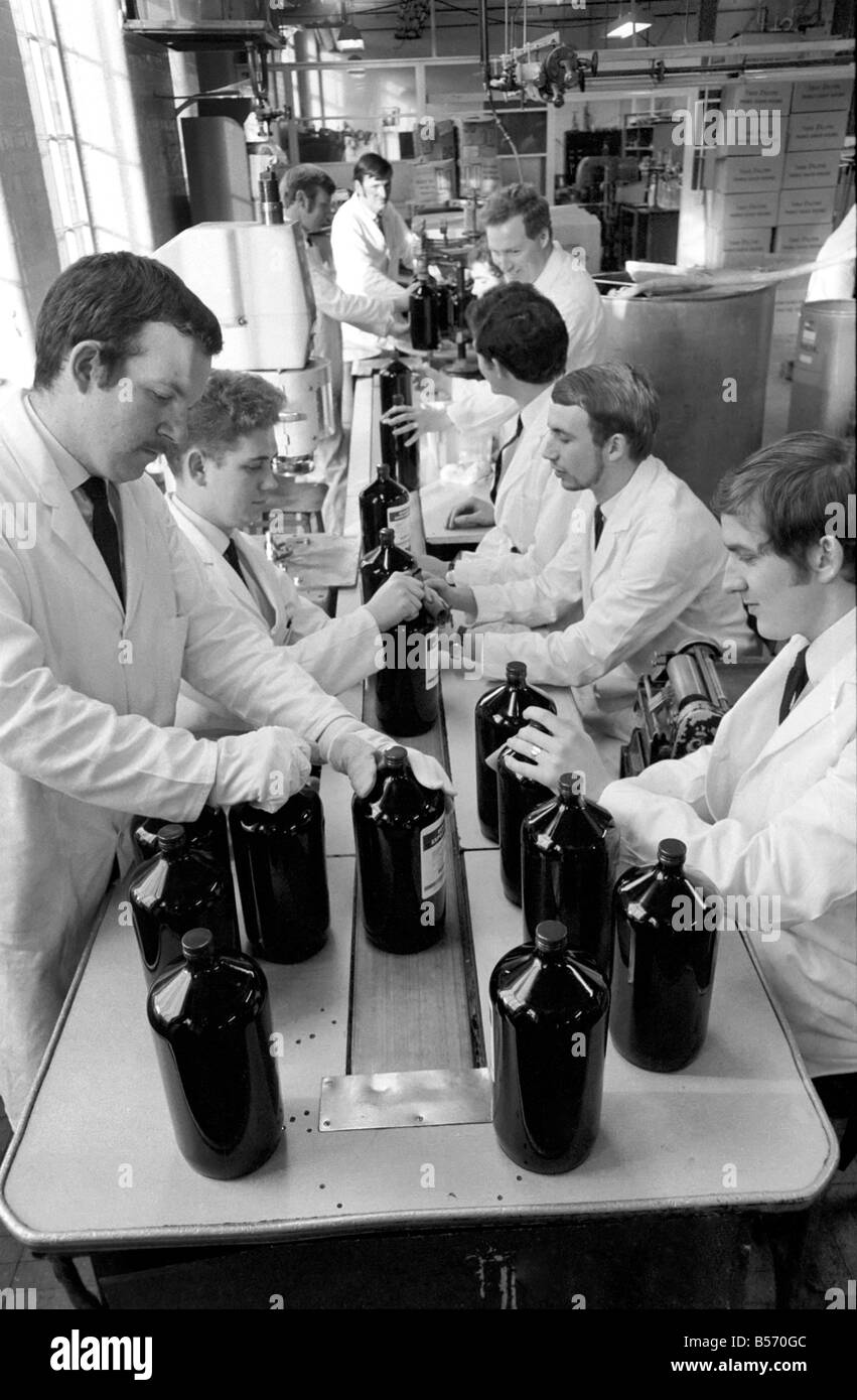 La recherche médicale : Une médecine célèbre les fabricants travaillent à plein régime pour faire face à la grippe aviaire epedemic. Leur remède contre la toux bien connu qui est prescrite par la plupart des médecins était de plus en plus difficile à obtenir, pour une formation complète les pharmaciens se sont portés volontaires pour aider à la mise en bouteille de ce médicament. Ces pharmaciens travaillent dans l'entreprise, Parke-Davis & Co., d'Hounslow, Middlesex et sont maintenant en train de mettre des étiquettes et bouchons sur le médicament... un travail normalement effectué par les femmes. 30 de leurs femmes sont là avec la grippe. Décembre 1969 Z12497 Banque D'Images