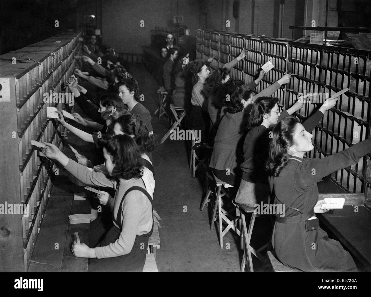 La Seconde Guerre mondiale, des femmes : bureau de poste prennent sur les filles à l'école à partir de l'âge de 14.A partir de faire le tri de Noël. Ils font un cours d'instruction et de le passer à la chambres de tri pour le travail. Ils travaillent de 9 à 5 et le L.C.C. ont aidé le bureau de poste en laissant les filles de leur école cours pour ce travail important qui a été principalement réalisé par les hommes. Scène dans la chambre d'instruction. Les filles apprennent avec des cartes marquées de diverses villes. Décembre 1943 P010264 Banque D'Images La Seconde Guerre mondiale, des femmes : bureau de poste prennent sur les filles à l'école à partir de l'âge de 14.A partir de faire le tri de Noël. Ils font un cours d'instruction et de le passer à la chambres de tri pour le travail. Ils travaillent de 9 à 5 et le L.C.C. ont aidé le bureau de poste en laissant les filles de leur école cours pour ce travail important qui a été principalement réalisé par les hommes. Scène dans la chambre d'instruction. Les filles apprennent avec des cartes marquées de diverses villes. Décembre 1943 P010264 Banque D'Images