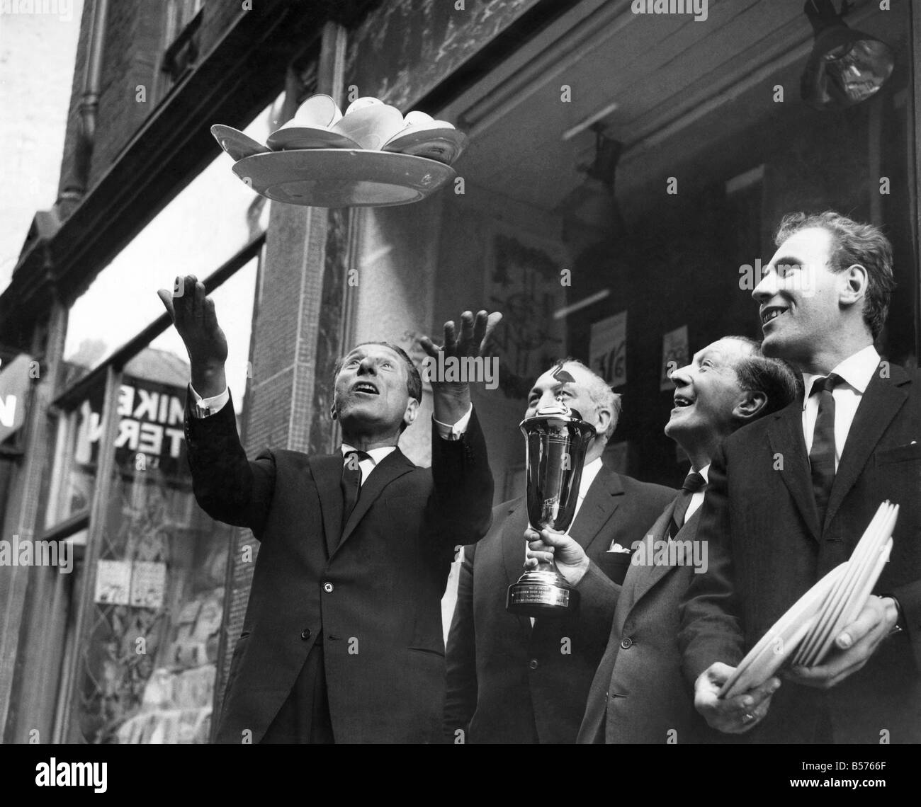 Les vendeurs de rue : Sid Strong lance en altitude un plateau rempli de tasses et soucoupes, l'une de ses tours qu'il effectue lors de la vente dans l'allée. Avril 1964 P004961 Banque D'Images