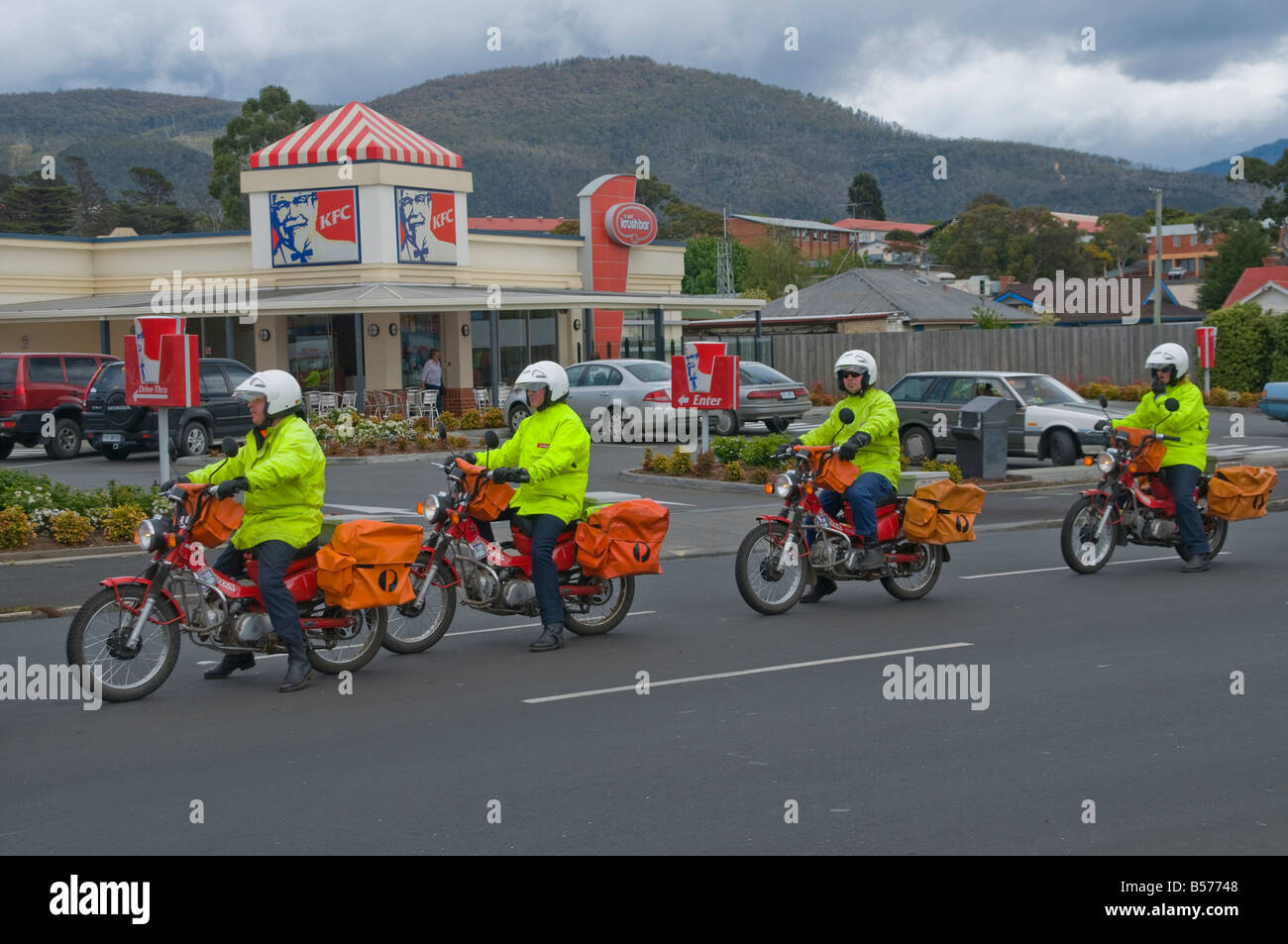 Une file de trois stagiaires débutants en livraison postale derrière un instructeur apprenant à conduire des motos et à livrer du courrier à Hobart Tasmanie Banque D'Images