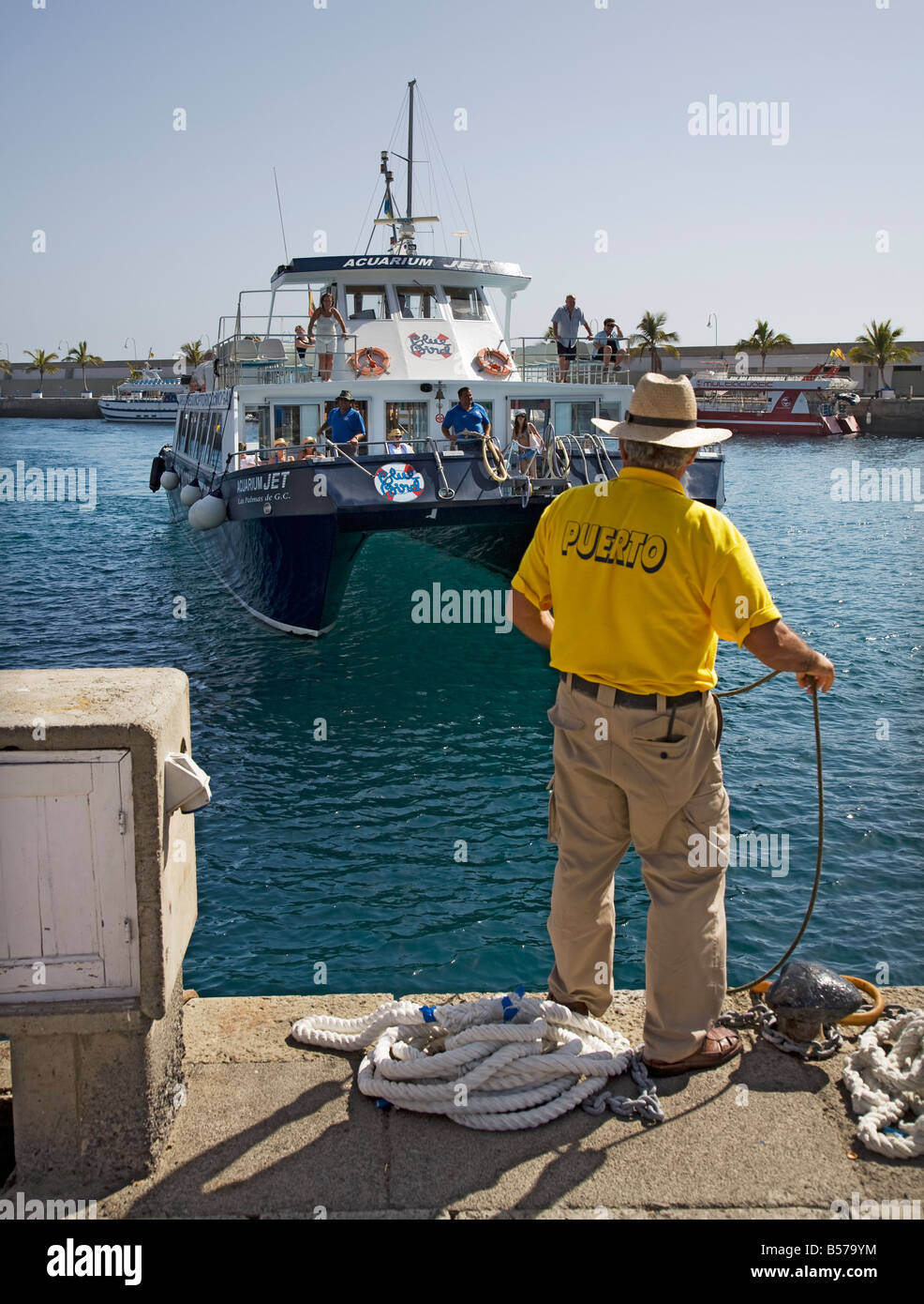 L'homme sur le quai avec corde prêt à attacher catamaran touristique Porto Rico Gran Canaria Espagne Banque D'Images