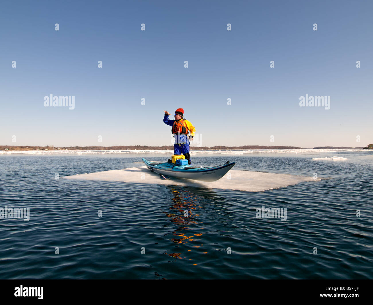 Homme debout à côté d'un kayak de mer en fibre de carbone sur une plaque de glace au milieu du fleuve Saint-Laurent. Banque D'Images