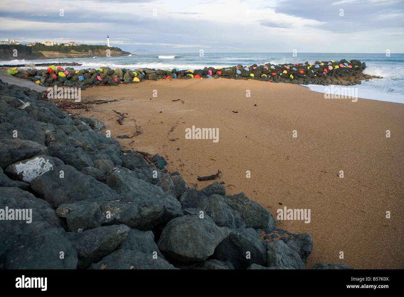 Les roches de couleur sur une jetée à Anglet avec le phare de Biarritz derrière Banque D'Images