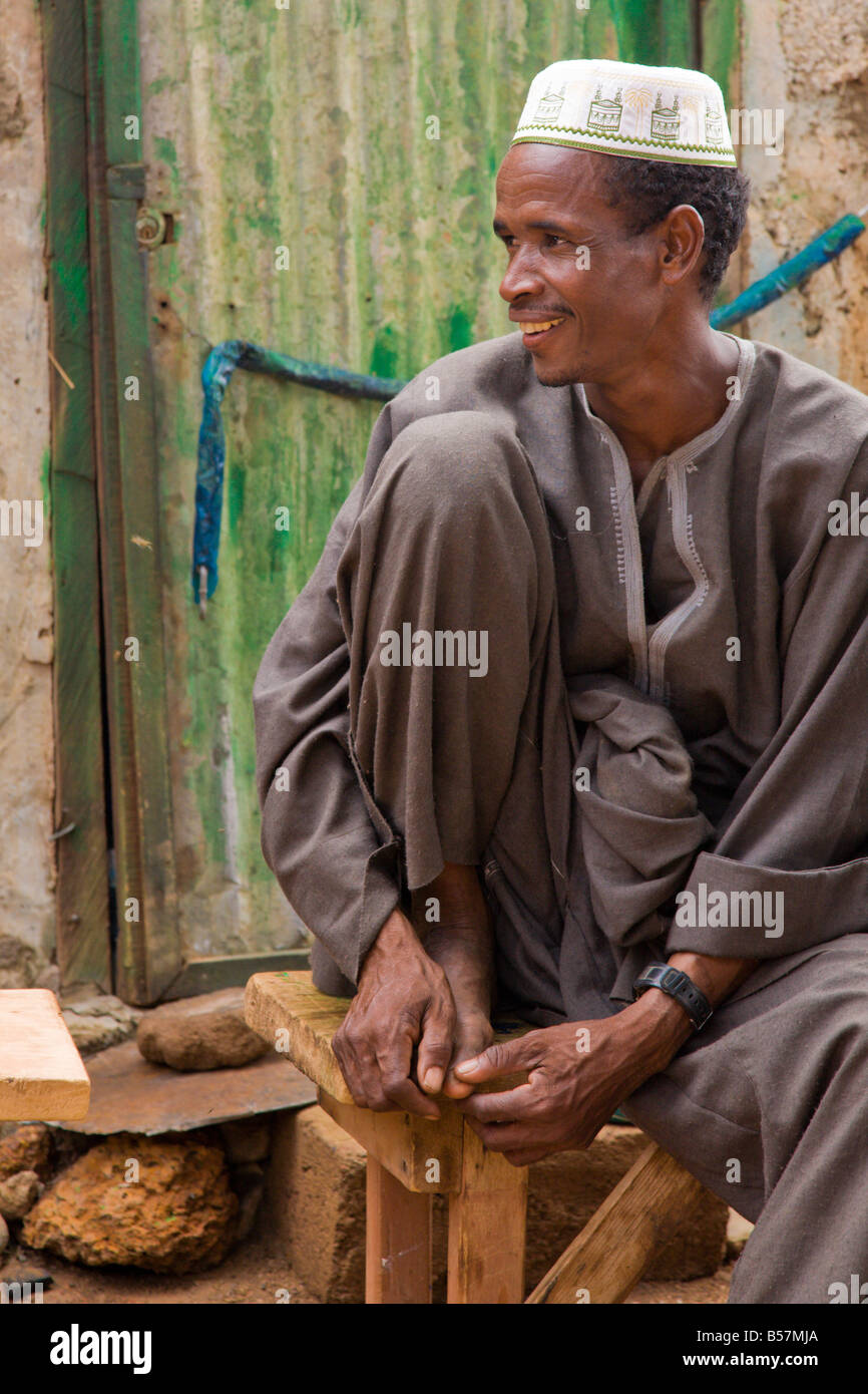 Un homme Peul se trouve dans un banc de bois dans la région de Ouagadougou Burkina Faso Banque D'Images