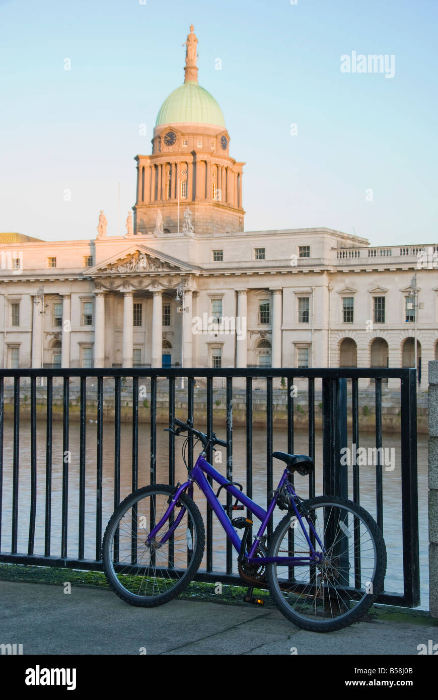 Un vélo verrouillé sur les rails à la recherche dans la direction de l'Custom House à Dublin Banque D'Images