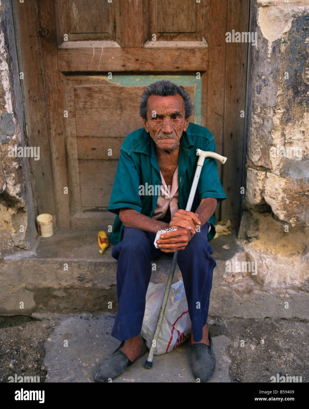 Portrait d'un homme âgé avec un bâton assis sur un démarchage des cigarettes dans la vieille Havane Cuba Antilles Banque D'Images