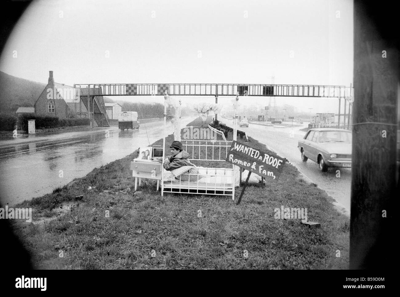 Romeo Meli accroupi contre la pluie battante dans un lit comme les camions de le percer à jour passé. C'est une sieste sur l'herbe de la division d'une double voie de chariot dans une tentative de sauver son vouée cottage. Il est le dernier homme de gauche regrettent la disparition de la déserté de Groes près de Port Talbot, Glam. Les 21 autres familles ont déjà quitté disparu. Avril 1975 75-1947-001 Banque D'Images