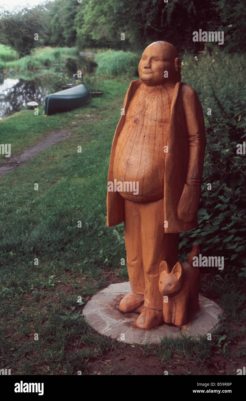 Statue en bois d'un gros homme et son chien debout à côté du chemin de halage du canal, près de Montgomery, Welshpool Powys, Pays de Galles Banque D'Images