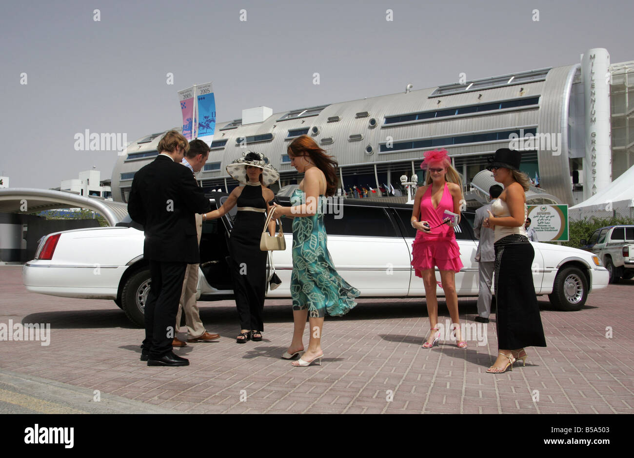 Les hommes et les femmes élégantes en face de l'entrée de la Nad Al Sheba horse race course, Dubaï, Émirats Arabes Unis Banque D'Images