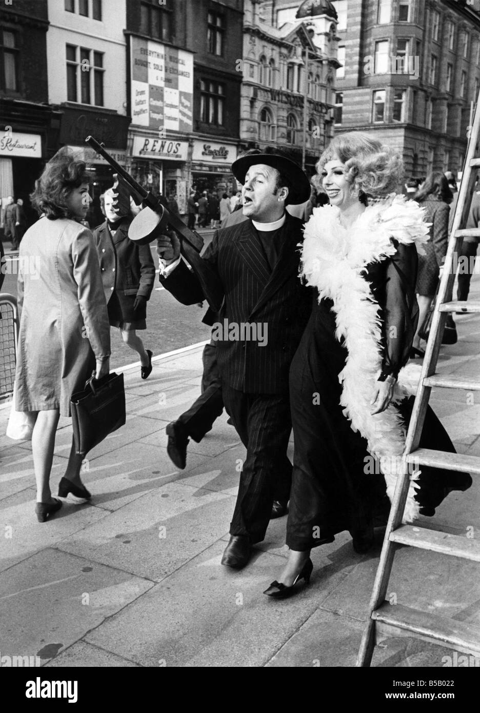 Tout est bon pour singer Marian Montgomery et Michael Segal (complet avec Tommy-gun) comme ils se promener à Manchester, à la grande consternation des passants ! Ils sont deux des stars de la musique de Cole Porter "anything goes" qui s'ouvre au Palace Theatre, Manchester Marian joue Reno Sweeney, un night club reine et Michael joue Moonface Martin, Public Enemy. Octobre 1969 P007325 Banque D'Images