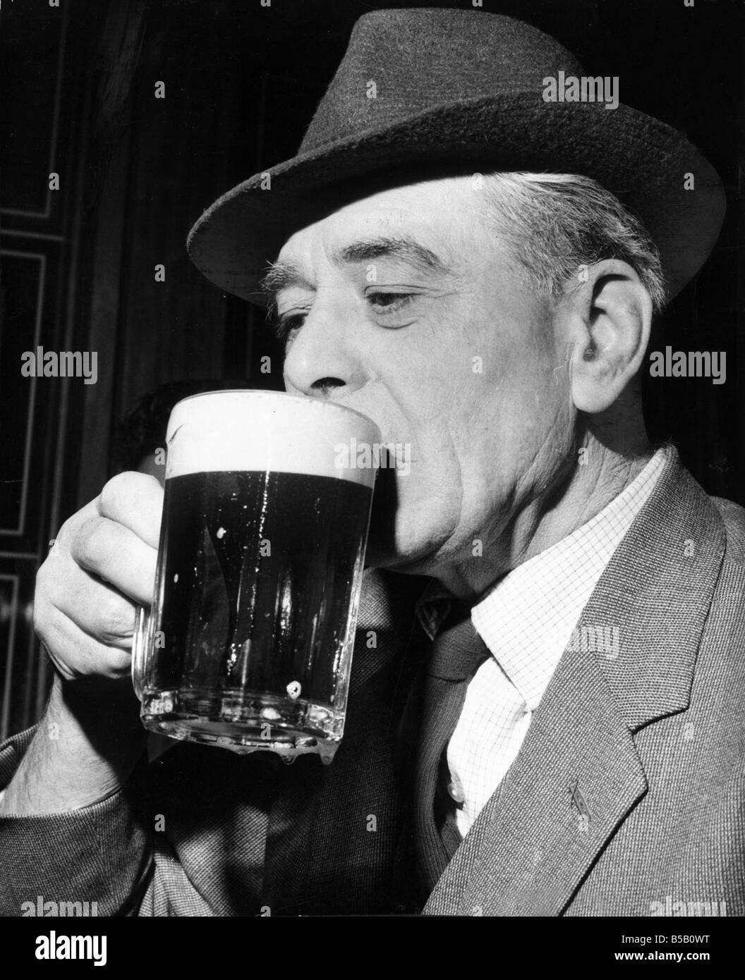 Un homme âgé bénéficie d'une pinte rafraîchissante à son pub local Avril 1964 Banque D'Images